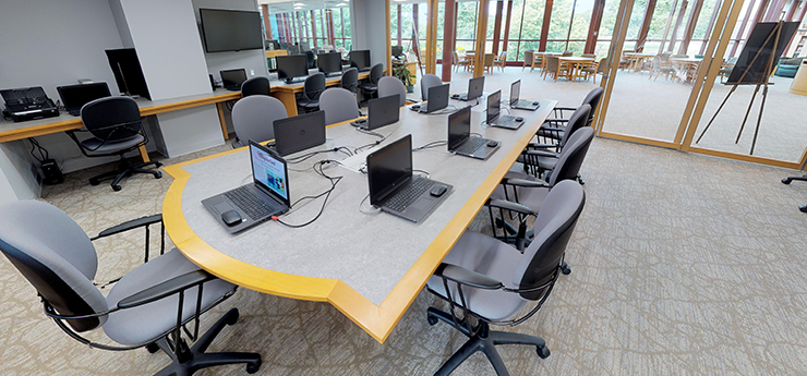 Technology center with long conference table and laptops in front of each chair