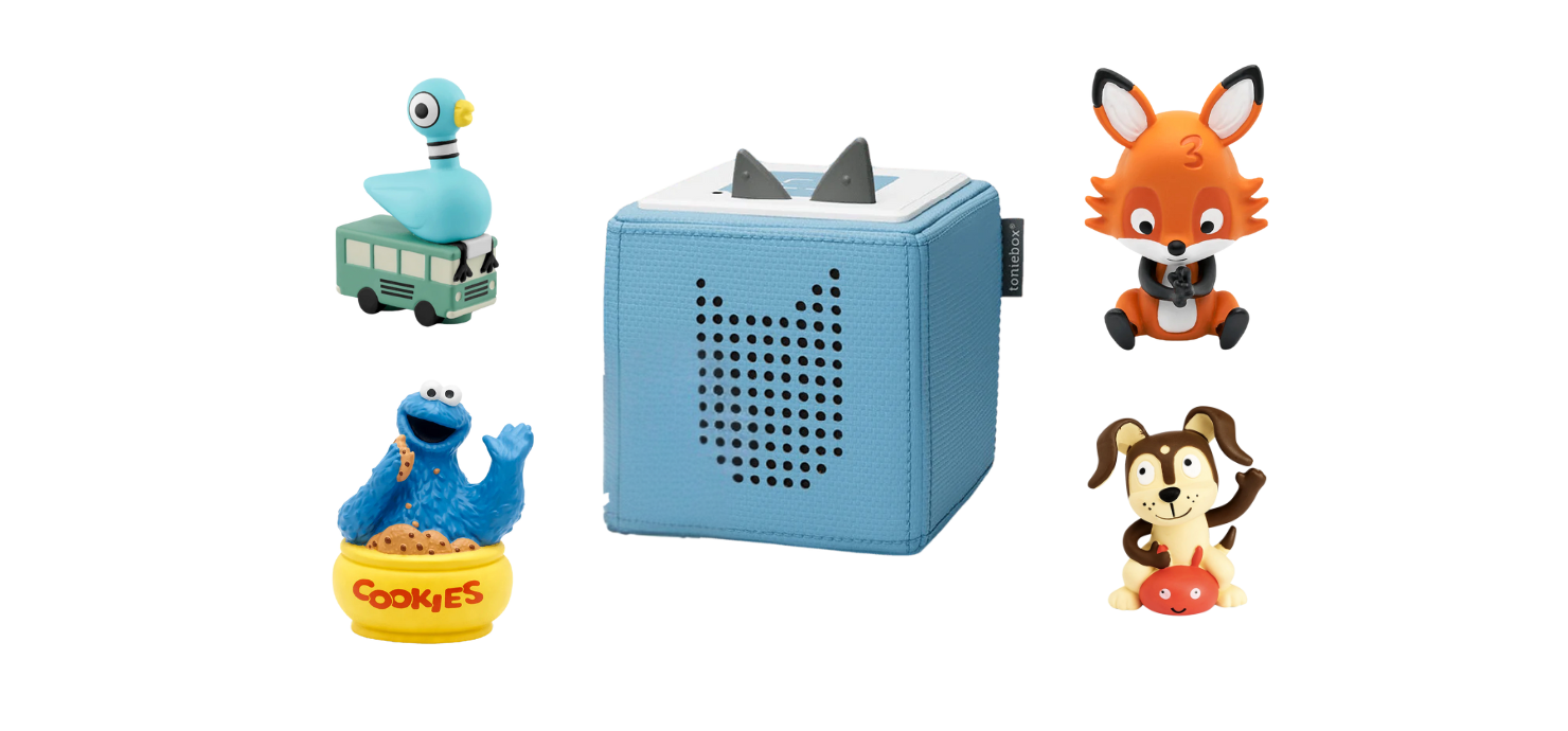  A light blue Toniebox audio player, cube-shaped with cat ears on top, is centered in the image. It is surrounded by four Tonies figures: The Pigeon (sitting on a green bus from Don't Let the Pigeon Drive the Bus!), Cookie Monster (sitting in a bowl of COOKIES), a fox, and a dog sitting on a red object.