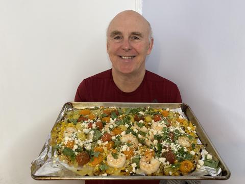 Chef Rob holding a plate of Garlic Shrimp with Corn, Cherry Tomatoes and Feta.