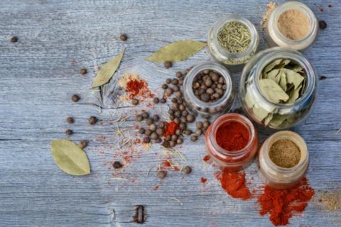 A photo of assorted spices in small round containers and jars.