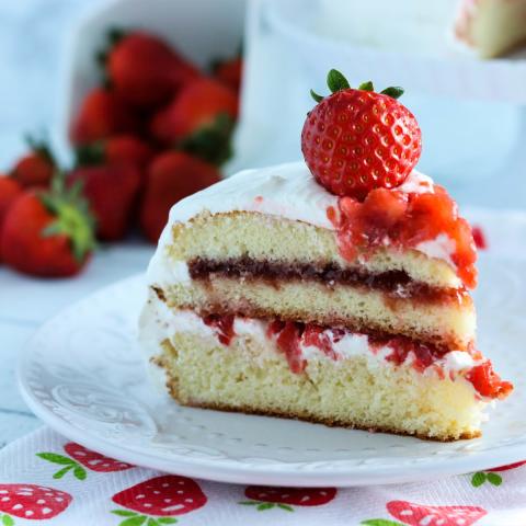 A color photo of a slice of strawberry shortcake on a white plate.