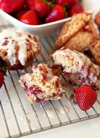 A photo of muffins on a cooling rack beside a bowl of strawberries.
