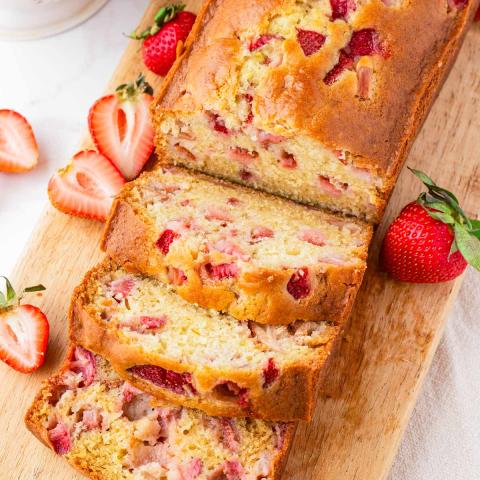 A color photo of a loaf of partially sliced strawberry bread.