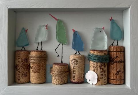 A diorama filled with sea glass birds sitting atop corks.
