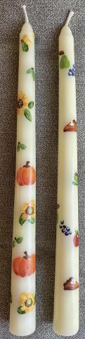 A pair of ivory taper candles painted with a fall motif.