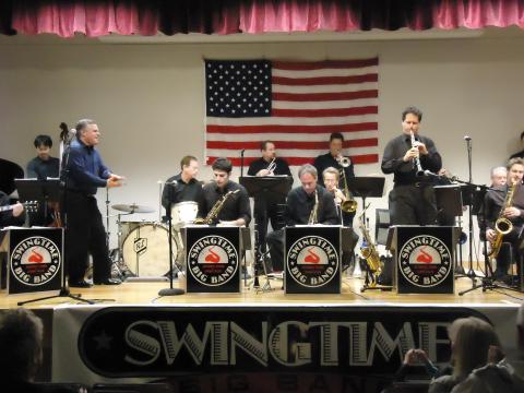 Members of the Swingtime Big Band on stage with an American flag in the background.