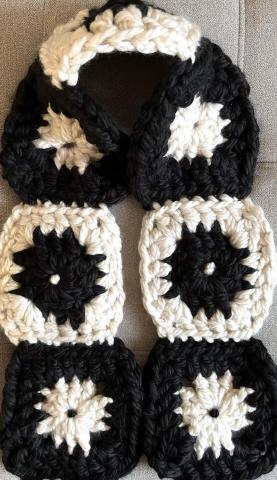 A photo of a scarf made with black and cream granny squares.