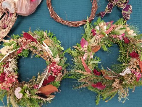 A phot of two holiday wreaths/centerpieces made with fresh greens and herbs.