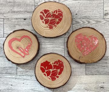 A color photo of four wood slice coasters stamped with hearts.