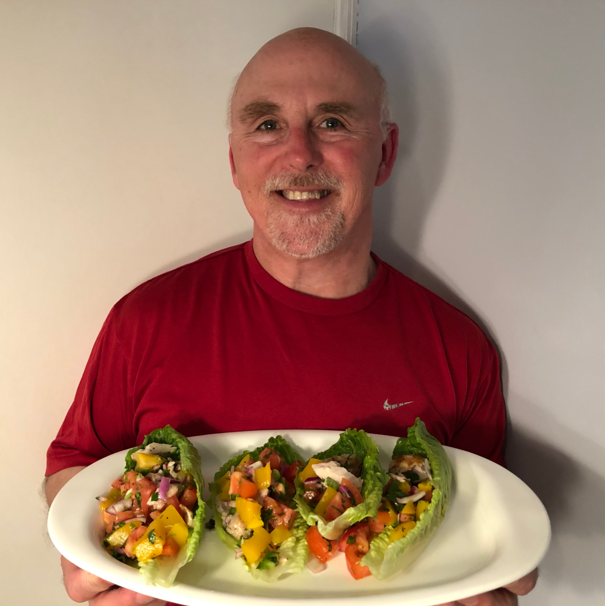 Photo of Chef Rob holding a plate of Mahi Mahi & Mango Lettuce Wraps.