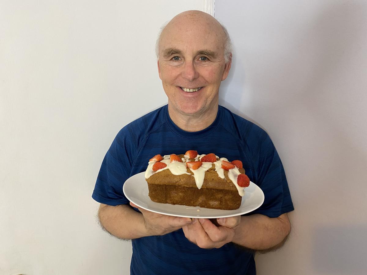 A photo of Chef Rob holding a white plate with a loaf of strawberry bread on it.