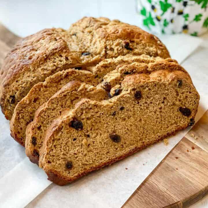 A color photo of a partially sliced loaf of Irish molasses bread on a wooden cutting board.