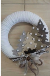 A white wreath adorned with a bow, felt tree cutouts and pearls.
