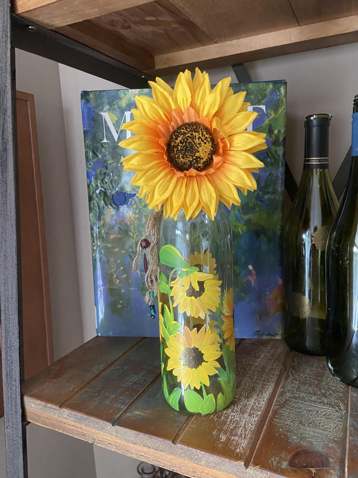A photo of a bottle painted with sunflowers.