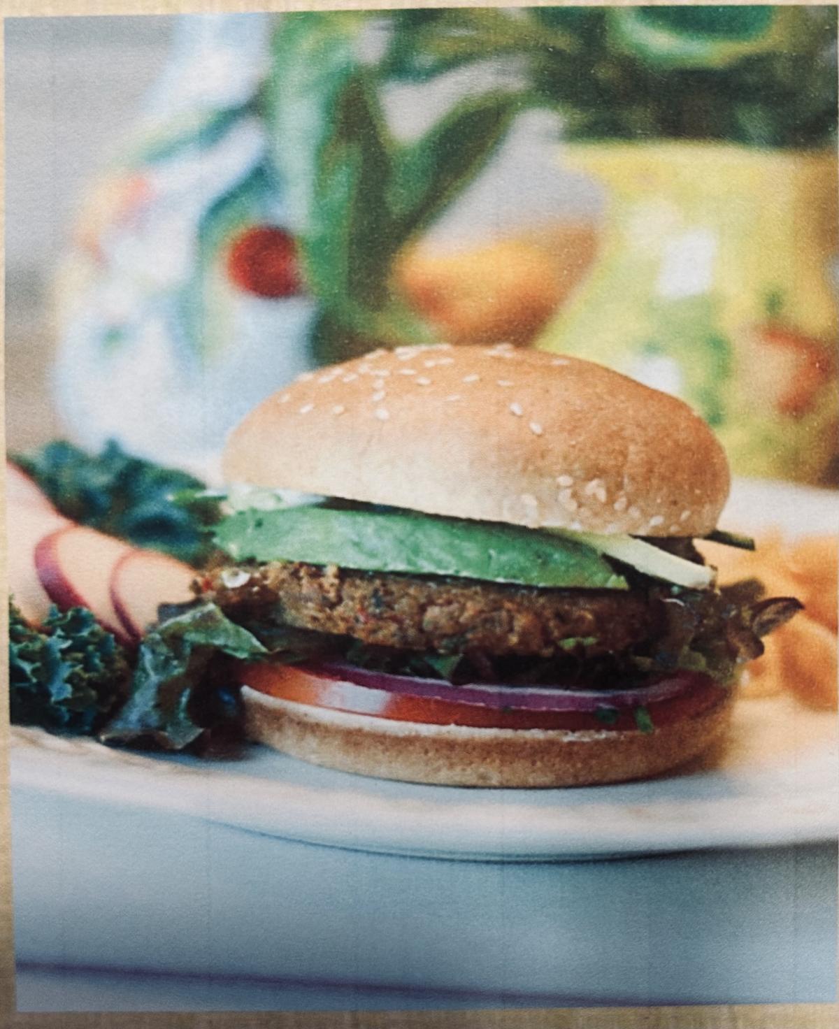 A picture of a veggie burger on a bun and sitting on a plate.
