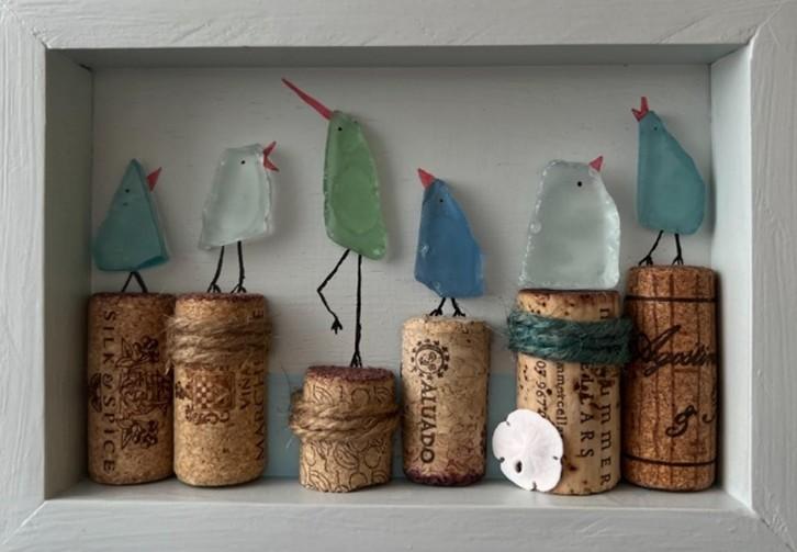 A diorama filled with sea glass birds sitting atop corks.