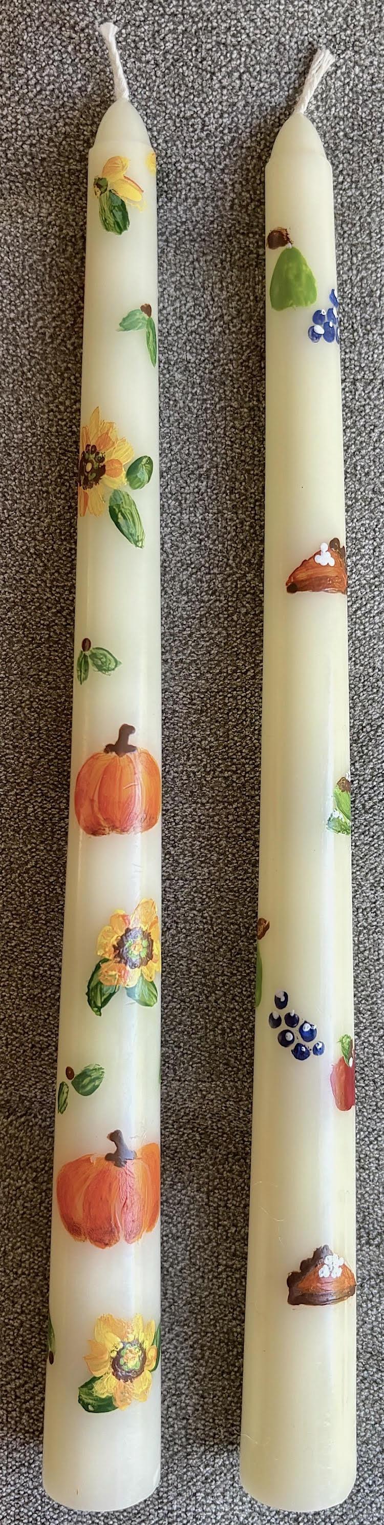 A pair of ivory taper candles painted with a fall motif.