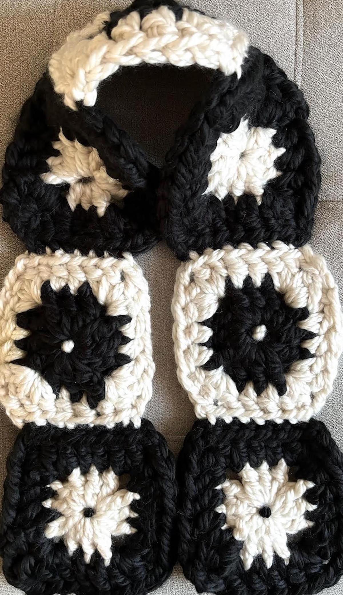 A photo of a scarf made with black and cream granny squares.
