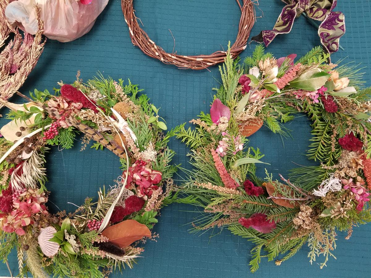 A phot of two holiday wreaths/centerpieces made with fresh greens and herbs.