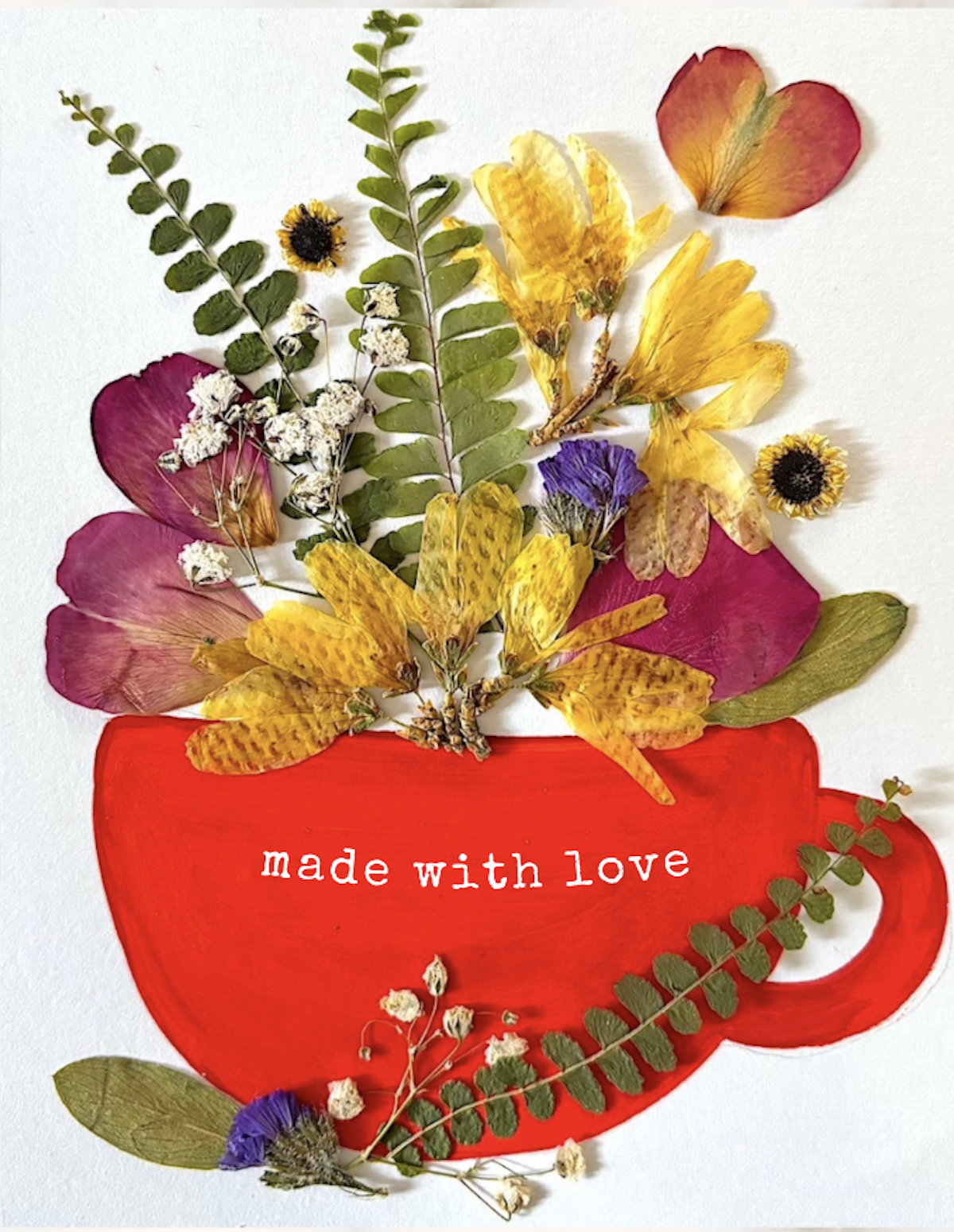 An image of a red hand-painted teacup adorned with pressed flowers and greenery.